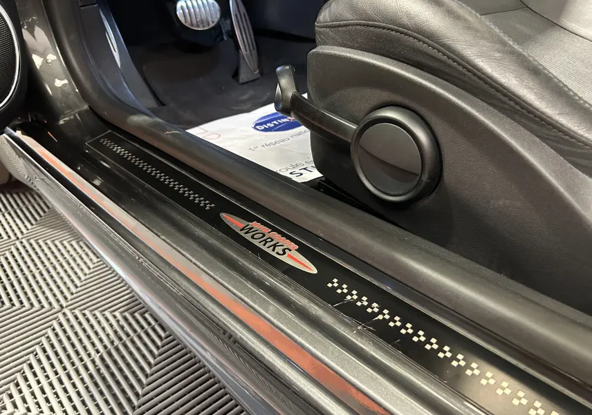 Vue intérieure côté gauche de la MINI Cooper gris avec seuil de porte marqué John Cooper Works et pédales sport en aluminium.