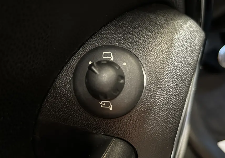 Gros plan sur le bouton de réglage des rétroviseurs noirs dans l'habitacle d'une MINI Cooper gris 2011.