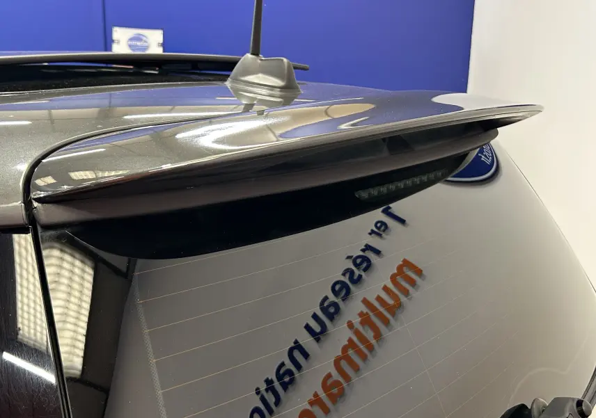 Vue rapprochée arrière droite d’une MINI Cooper gris métallisé avec aileron et antenne sur le toit.