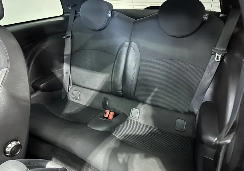 Vue intérieure arrière de la banquette noire de la MINI Cooper 2011 avec appuie-têtes ronds et ceintures visibles.