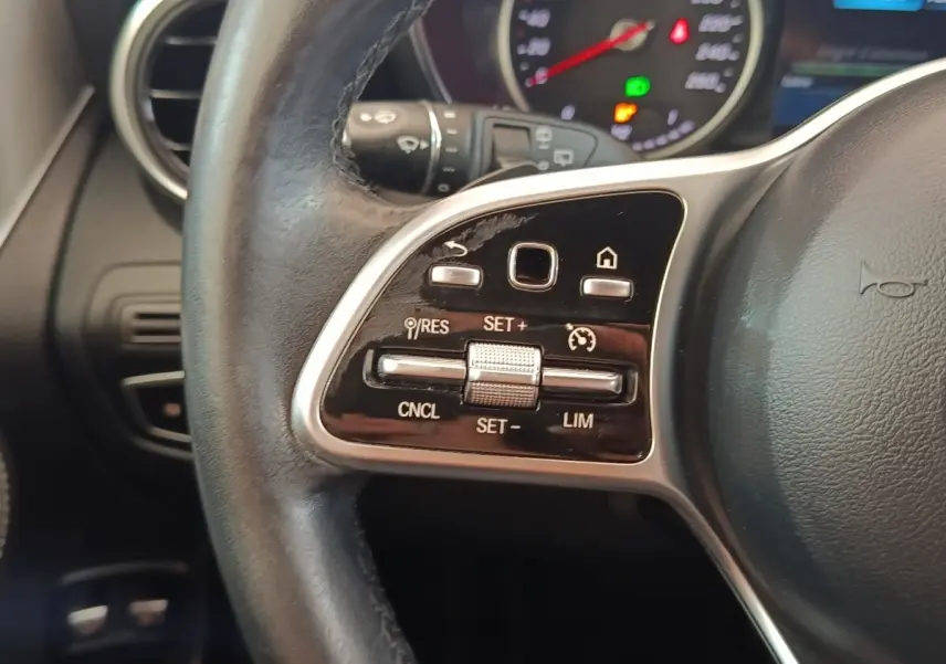 Gros plan sur la partie gauche du volant cuir noir d’un Mercedes GLC 300 hybride, avec commandes de régulateur de vitesse.
