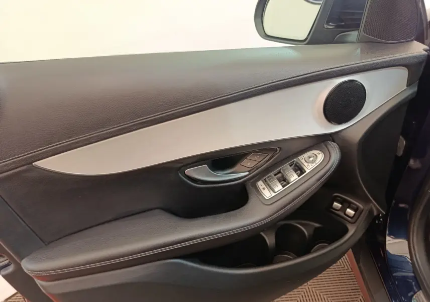 Vue intérieure côté gauche de la porte avant d’un Mercedes GLC bleu, avec garniture noire et insert aluminium.