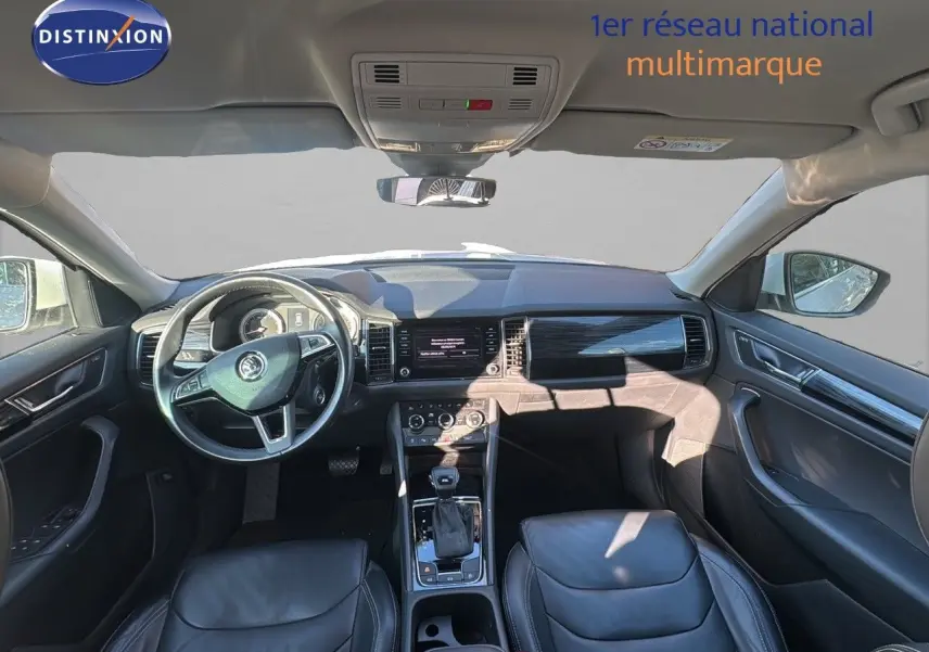 Intérieur du Skoda Kodiaq blanc 2018 vu de face, tableau de bord moderne avec volant multifonction et sièges cuir noir.