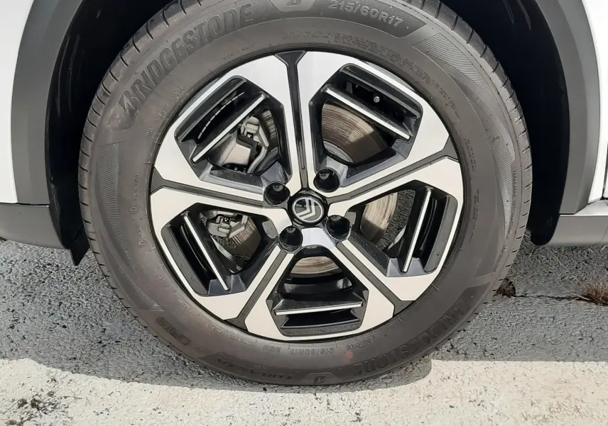 Gros plan sur la roue avant droite de la Citroën C3 Aircross blanc banquise avec jante alliage noire et argentée.