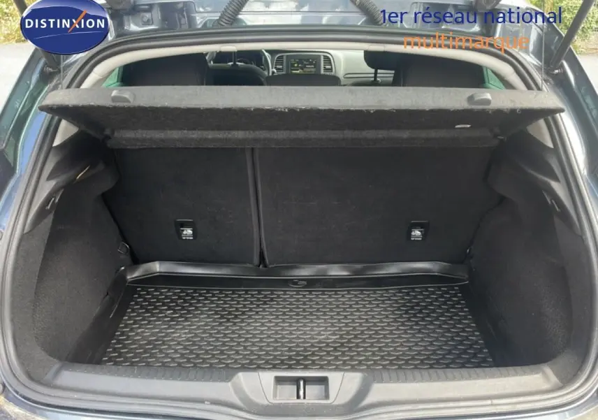 Coffre ouvert vu de l'arrière d'une Renault Mégane gris titanium, montrant un espace de chargement propre et vide.