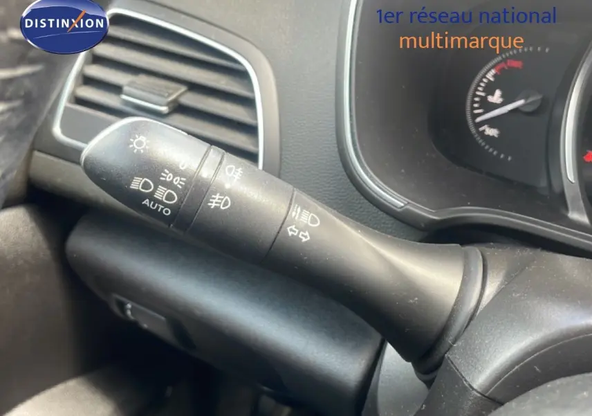 Gros plan sur la commande des phares et clignotants à gauche du volant dans l’habitacle d’une Renault Mégane gris titanium.