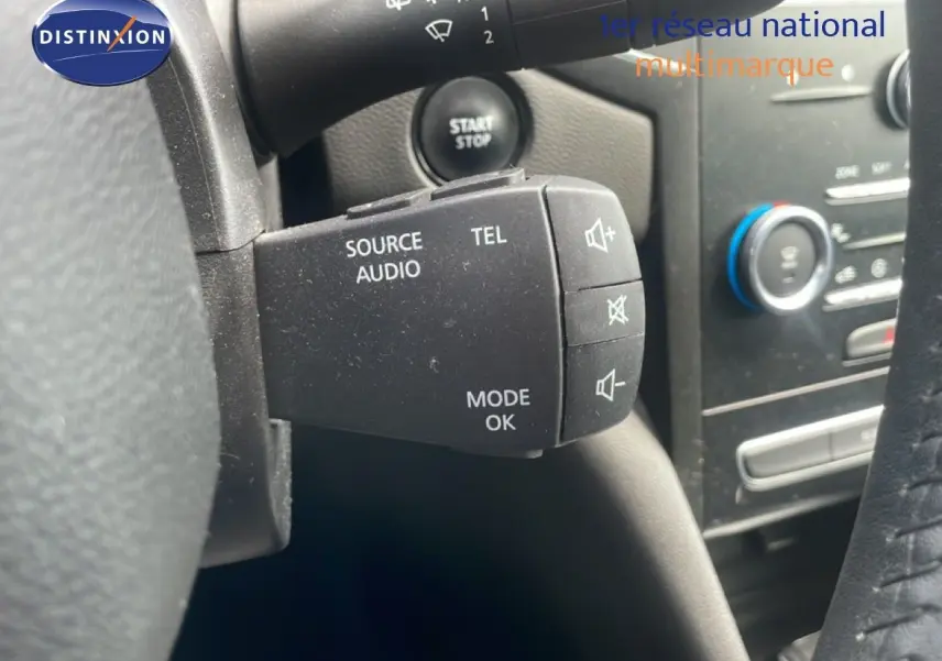 Gros plan sur la commande audio au volant d’une Renault Mégane gris titanium, avec démarrage sans clé visible.