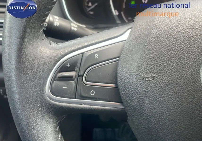 Gros plan sur le volant en cuir noir de la Renault Mégane 1.3 TCE 115ch, montrant les commandes de régulateur de vitesse.