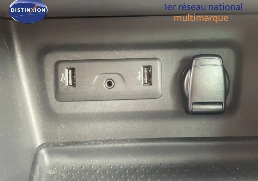 Détail intérieur montrant deux ports USB, une prise jack et une prise 12V sur fond plastique gris.