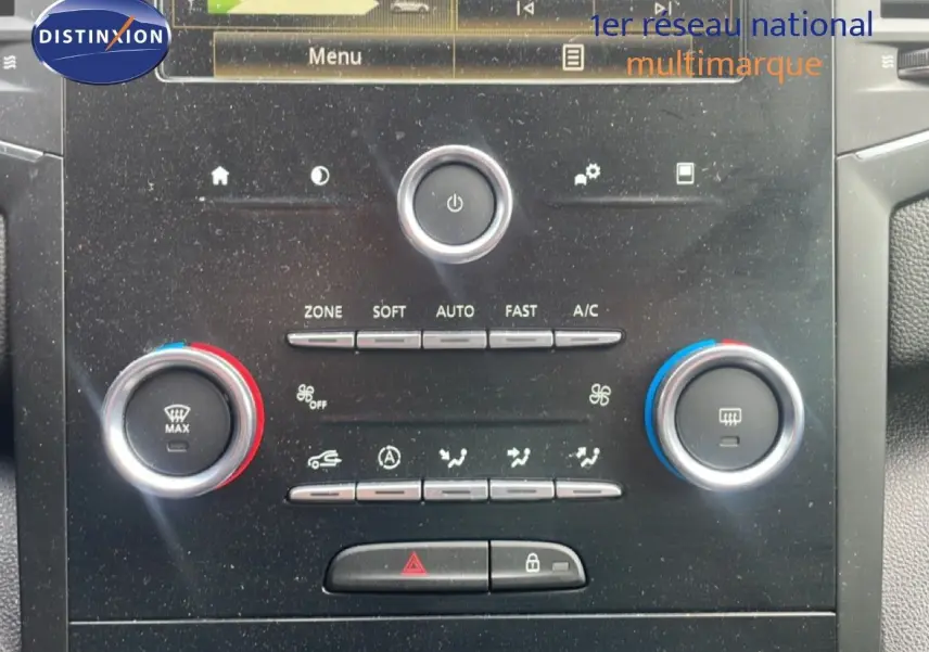 Vue rapprochée de la console centrale de la Renault Mégane gris titanium, montrant les commandes de climatisation et l’écran multimédia.