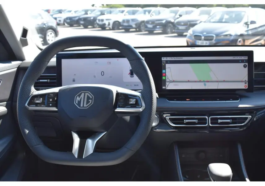 Vue intérieure centrée sur le volant noir MG avec tableau de bord numérique et écran tactile large affichant la navigation.