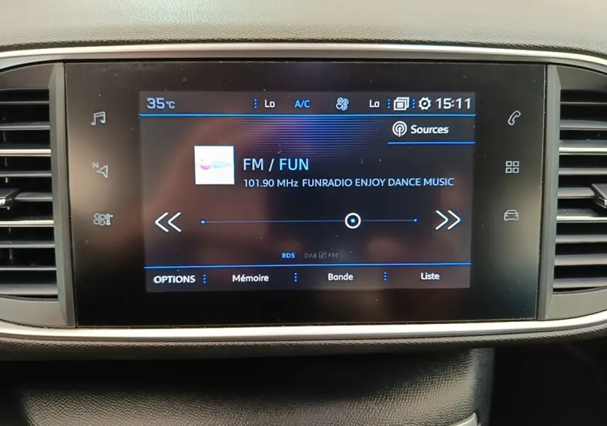 Écran tactile central de la Peugeot 308 blanc, affichant la radio FM avec interface moderne et commandes tactiles.