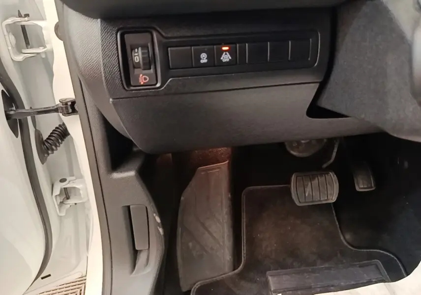 Vue intérieure côté conducteur de la Peugeot 308 blanche, montrant les pédales et commandes sous le tableau de bord.