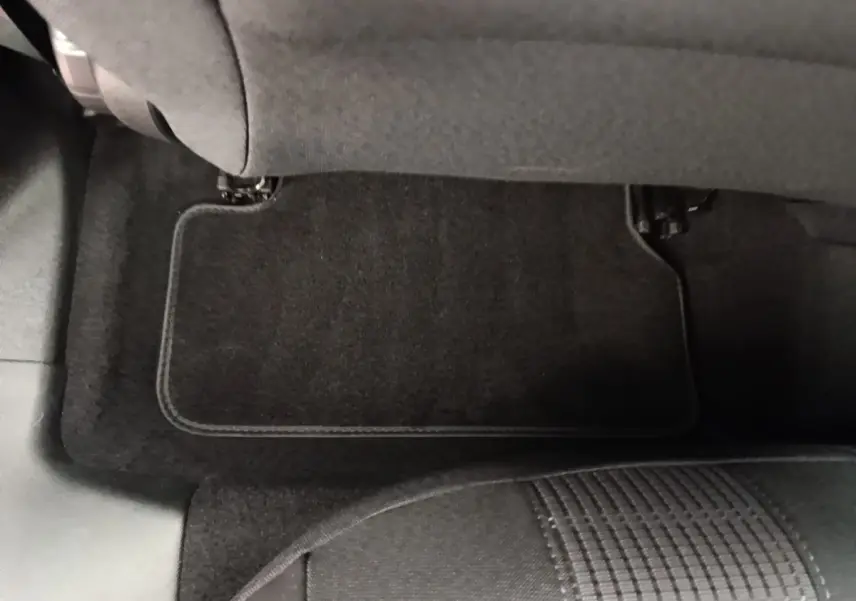 Vue rapprochée du tapis de sol arrière côté gauche de la Peugeot 308 blanche, avec siège tissu gris visible.