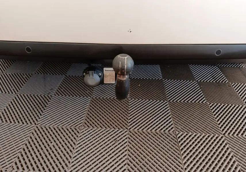 Gros plan sur l'attelage noir fixé à l'arrière d'une Peugeot 308 blanche, avec prise électrique visible à gauche.