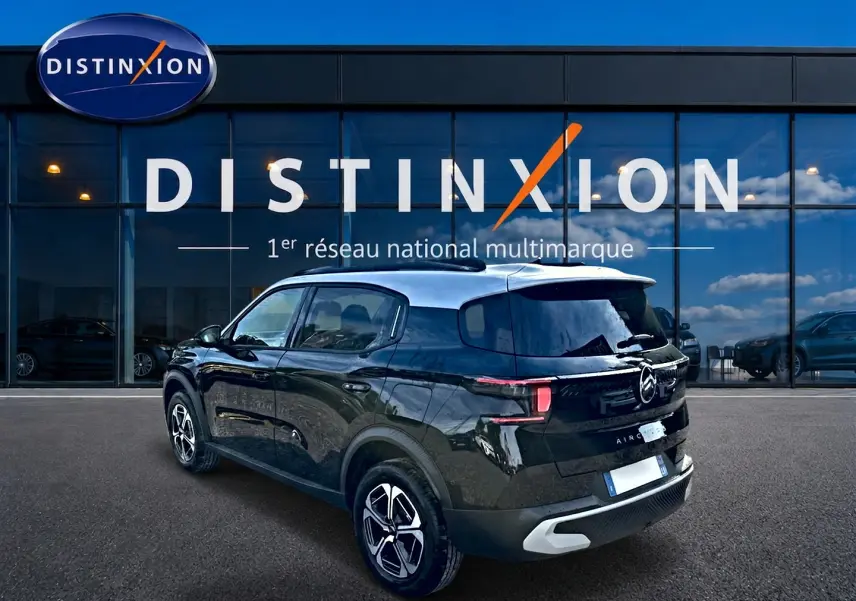 Vue 3/4 arrière droite d'une Citroën C3 Aircross noire 2026 avec jantes alu et vitres arrière teintées devant un showroom Distinxion.