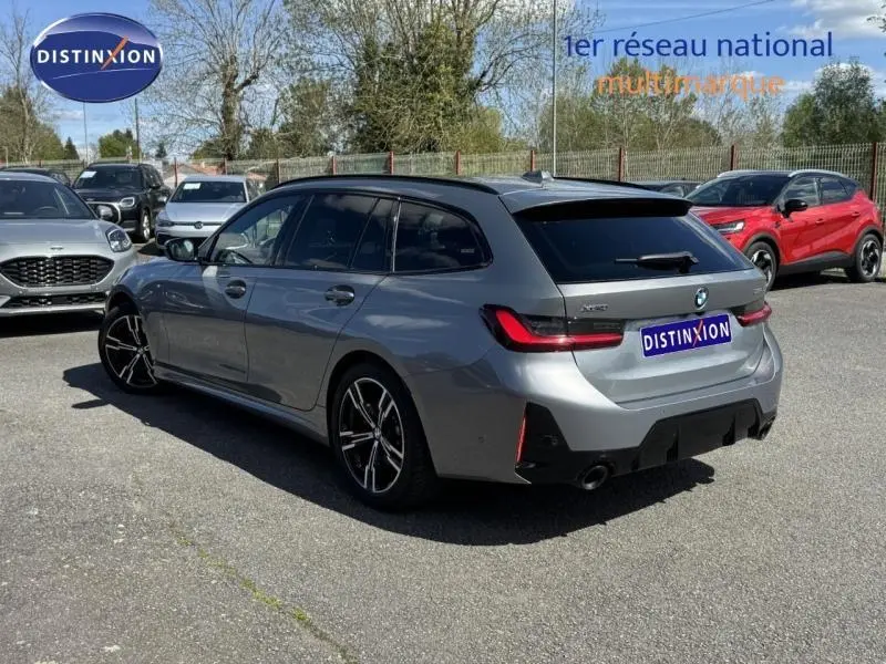 BMW Série 3 320dA xDrive M Sport grise métallisée vue 3/4 arrière droit sur parking extérieur.