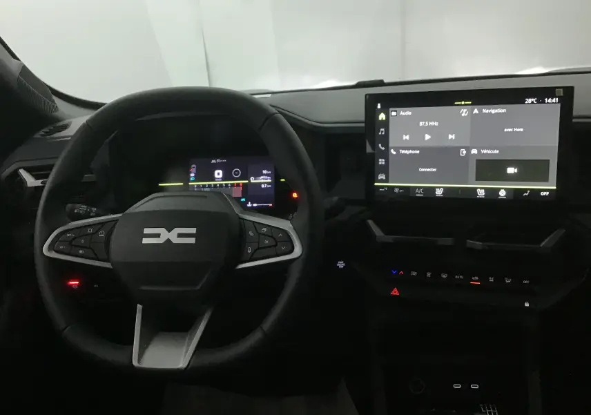 Vue intérieure centrée sur le volant multifonction et l'écran tactile du tableau de bord du Dacia Duster 2025.