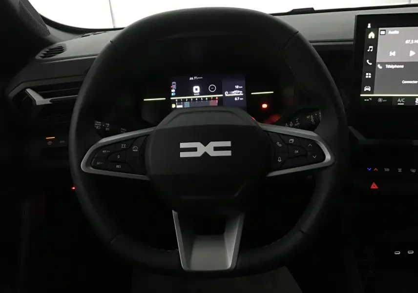 Vue rapprochée du volant noir du Dacia Duster 2025 avec tableau de bord numérique et écran tactile central.