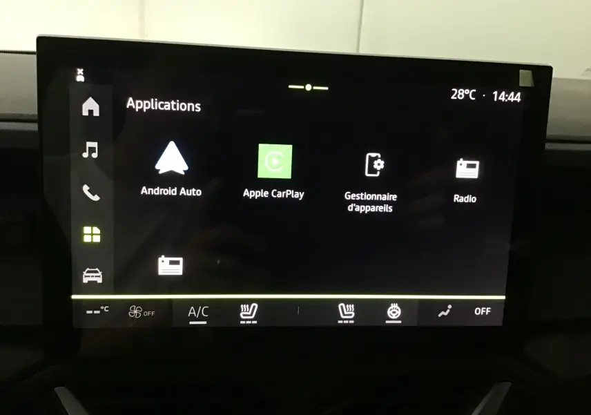 Écran tactile central du Dacia Duster 2025 affichant les applications Android Auto, Apple CarPlay et radio, avec commandes climatisation visibles.