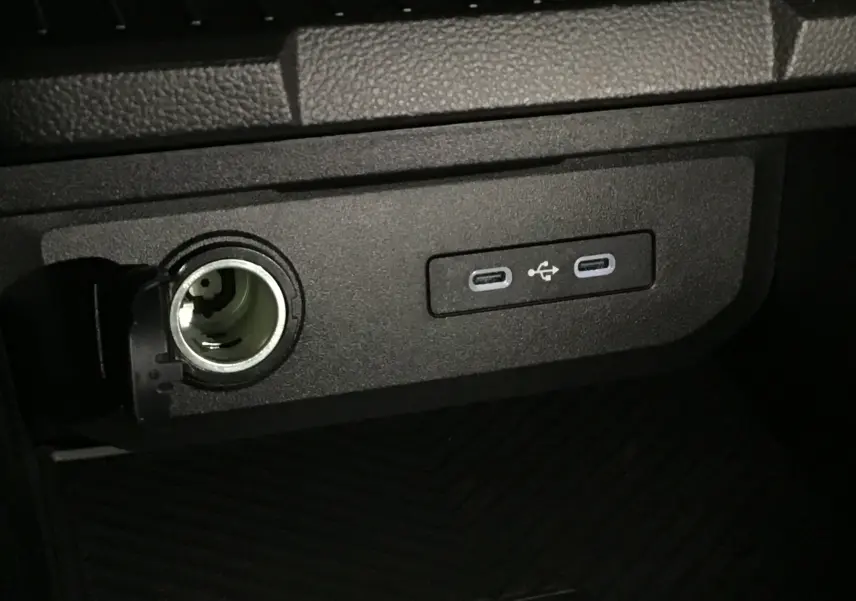 Prise allume-cigare ouverte et deux ports USB-C intégrés dans la console centrale du Dacia Duster 2025.