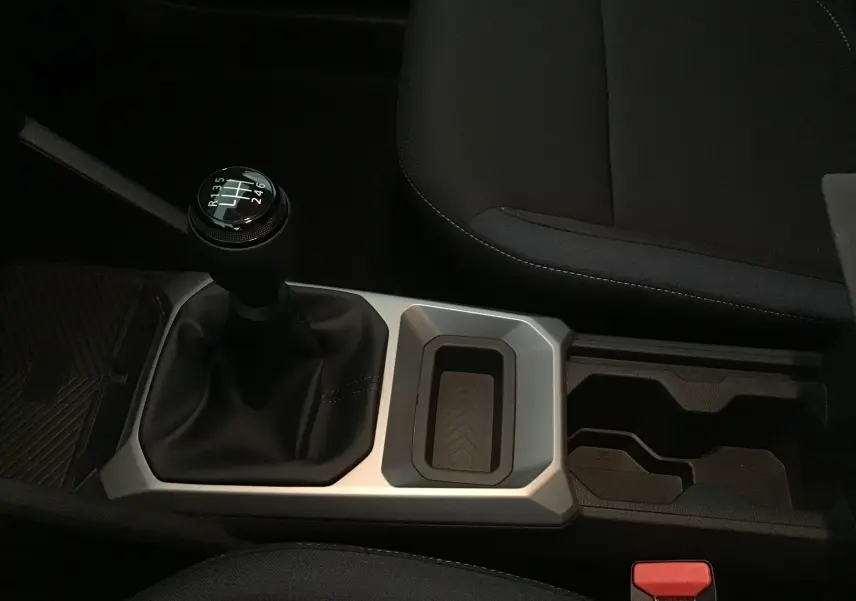 Gros plan sur la console centrale du Dacia Duster 2025 avec levier de vitesses manuel et sièges noirs.