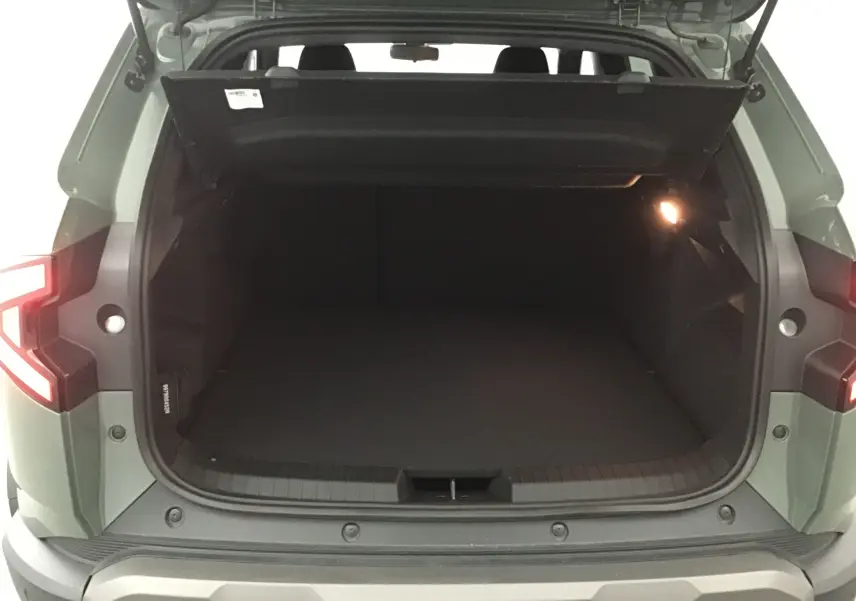 Coffre ouvert vu de l'arrière d'un Dacia Duster 2025 kaki lichen avec éclairage intérieur et hayon relevé.