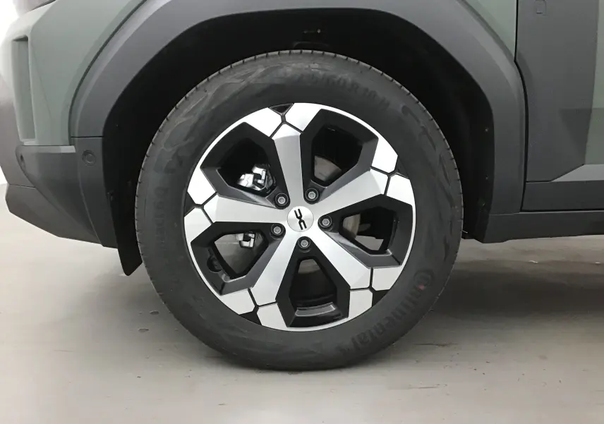Gros plan sur la roue avant gauche du Dacia Duster 2025 kaki lichen, avec jante alliage au design géométrique noir et argent.