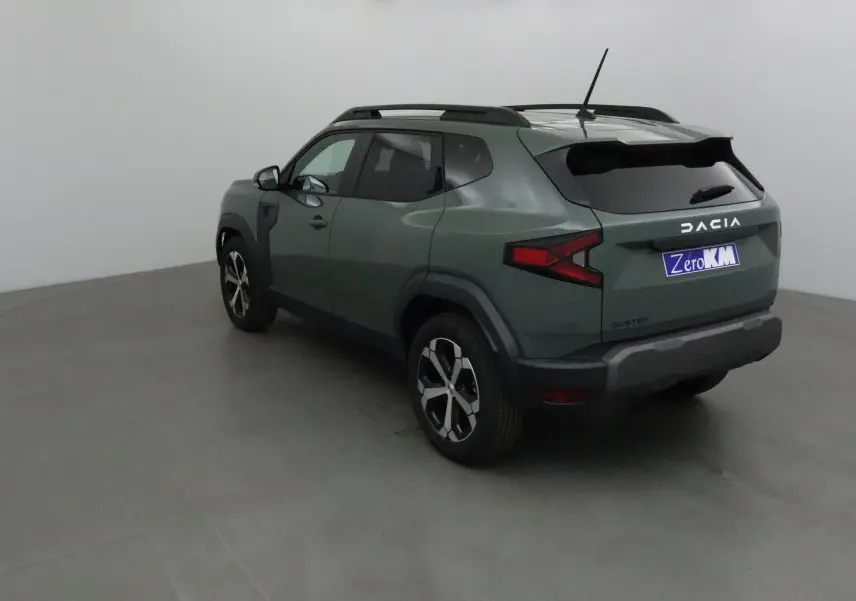 Vue 3/4 arrière gauche d'un Dacia Duster 2025 kaki lichen avec jantes alliage et barres de toit noires.