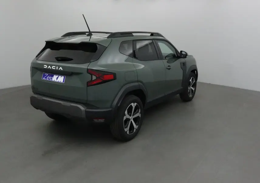 Vue 3/4 arrière droite du Dacia Duster 2025 kaki lichen avec barres de toit et jantes noires et argentées.