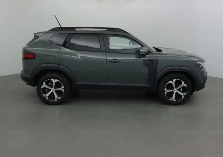 Profil droit du Dacia Duster 2025 en kaki lichen avec jantes alliage et barres de toit noires.