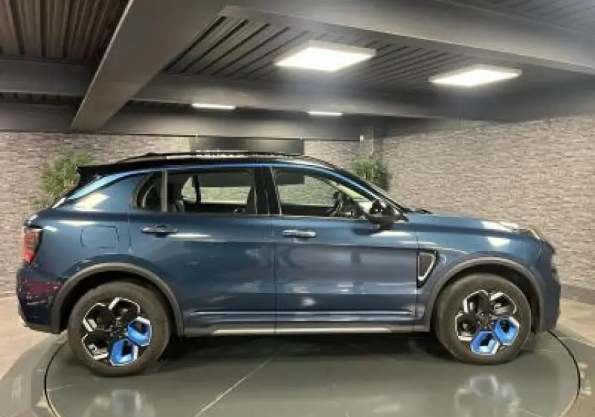 Profil côté gauche du SUV Lynk & Co 01 bleu métallisé avec jantes 20 pouces bicolores en intérieur lumineux.