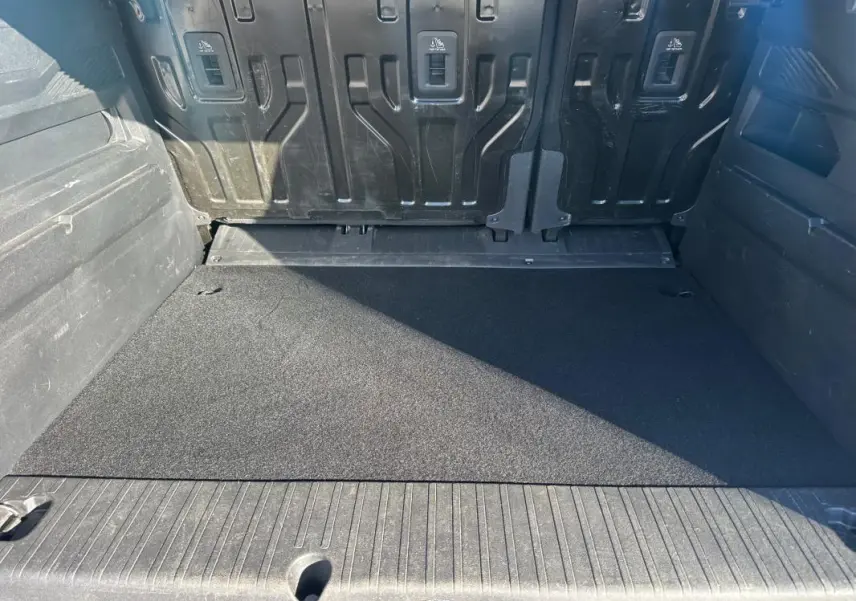 Coffre vu de l'arrière d'un Citroën Berlingo gris clair 2020, avec plancher plat et parois en plastique noir.