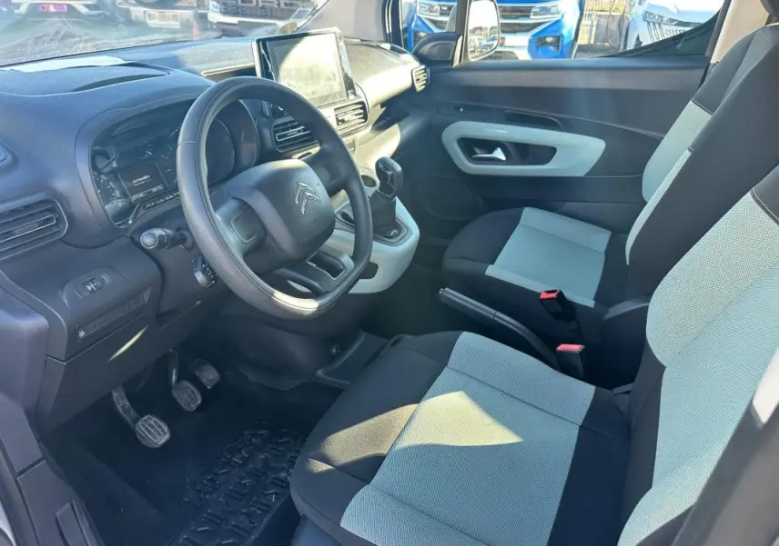 Vue intérieure côté conducteur du Citroën Berlingo gris clair 2020, montrant le volant, tableau de bord et sièges bi-ton.