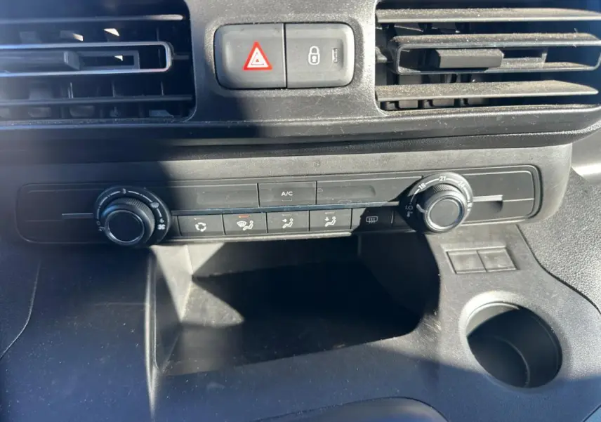 Vue rapprochée de la console centrale du Citroën Berlingo gris clair 2020, montrant les commandes de climatisation et les aérateurs.