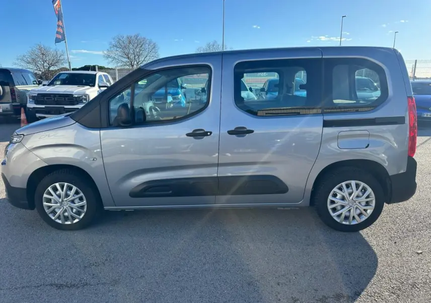 Vue de profil côté gauche d'un Citroën Berlingo gris clair 2020 avec protections noires sur les portes et jantes alliage.
