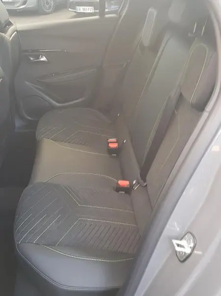 Vue intérieure côté gauche des sièges arrière en tissu et cuir noir du Peugeot 208 Hybrid 110 e-DCS6 GT gris 2025, avec ceintures rouges.