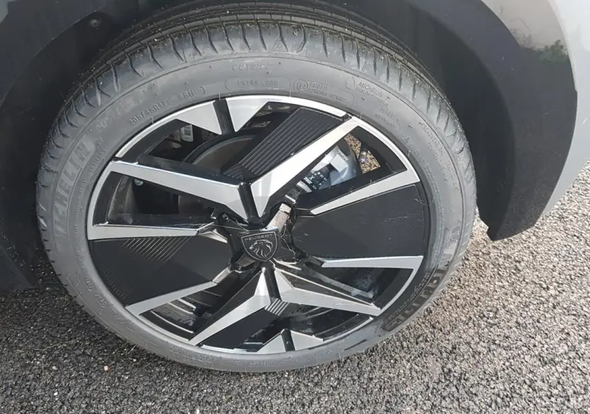 Gros plan sur la jante alliage noire et argentée de 17 pouces d'une Peugeot 208 gris, version Hybrid 110 e-DCS6 GT.