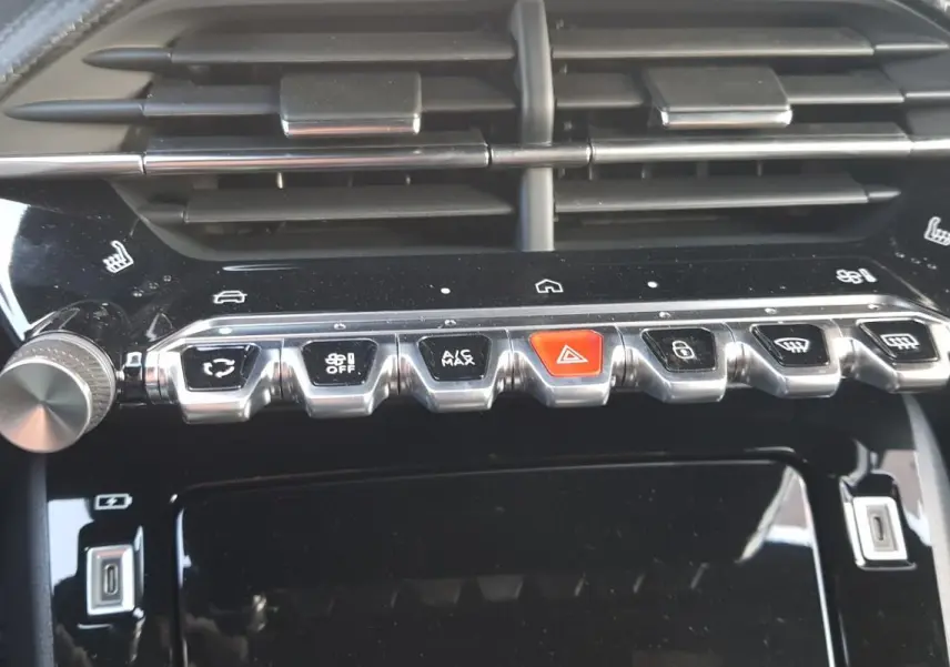 Gros plan sur la console centrale noire de la Peugeot 208 Hybrid 110 e-DCS6 GT avec boutons de climatisation et commandes tactiles.