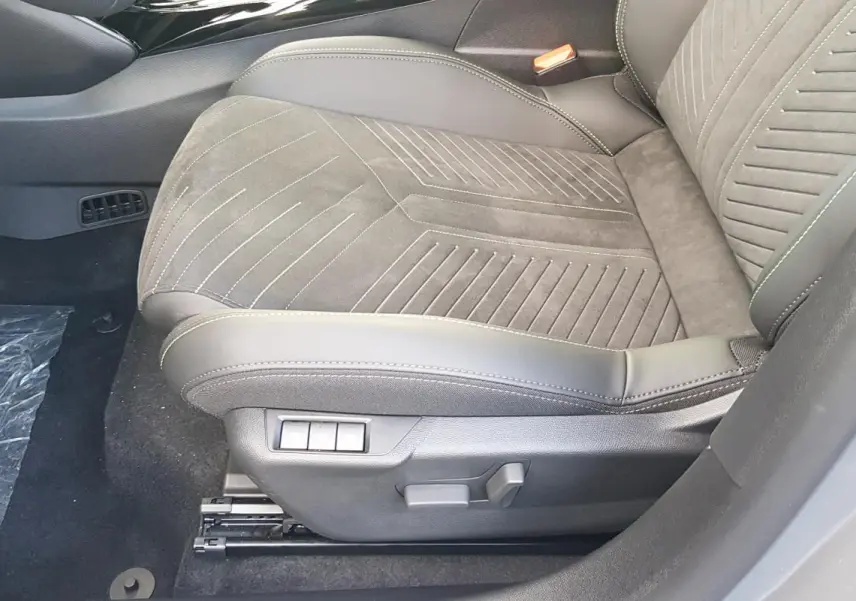 Gros plan sur le siège avant droit gris de la Peugeot 208 Hybrid 110 e-DCS6 GT avec réglages électriques visibles.