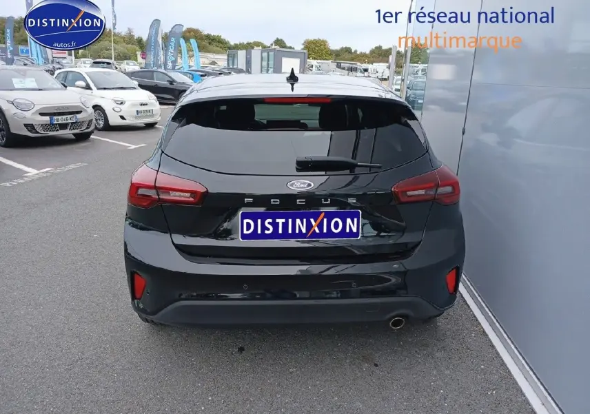 Vue arrière d'une Ford Focus noire Agate métallisé garée près d'un mur, avec feux arrière LED visibles.