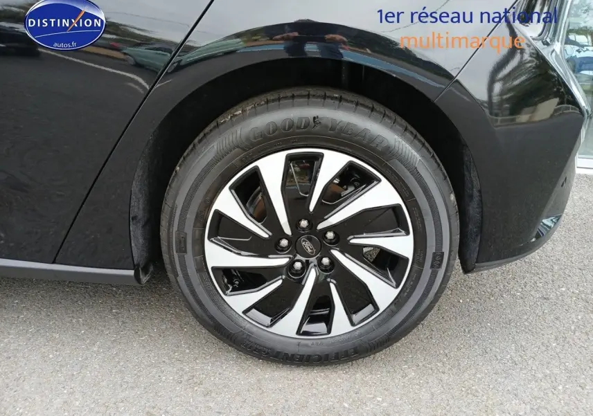 Gros plan sur la roue avant droite noire avec jante alliage bicolore d'une Ford Focus noir Agate métallisé.