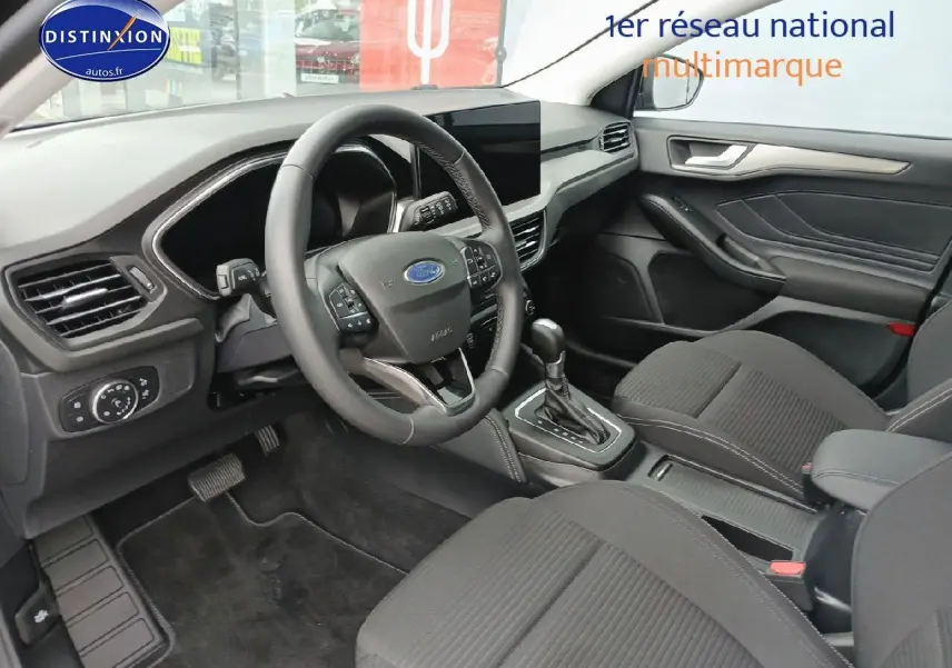 Vue intérieure côté conducteur de la Ford Focus 2024 noir Agate, volant cuir multifonction et console centrale visible.