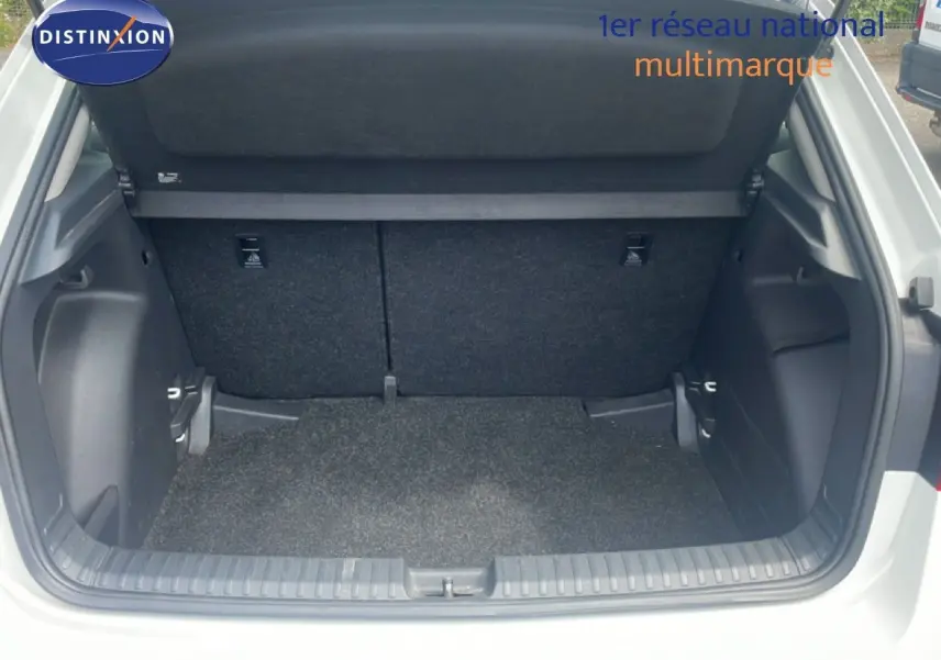 Coffre ouvert d’une Skoda Fabia blanc candy, vue arrière montrant l’espace de chargement vide et le cache-bagages relevé.
