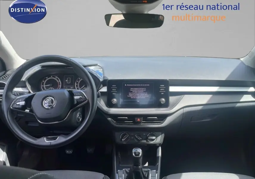 Intérieur de la Skoda Fabia 2022 blanc candy, vue frontale du tableau de bord avec volant cuir et écran tactile central.