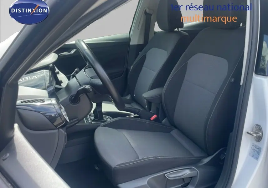 Intérieur côté conducteur d'une Skoda Fabia blanche 2022, sièges tissu noir et gris, volant cuir multifonction.
