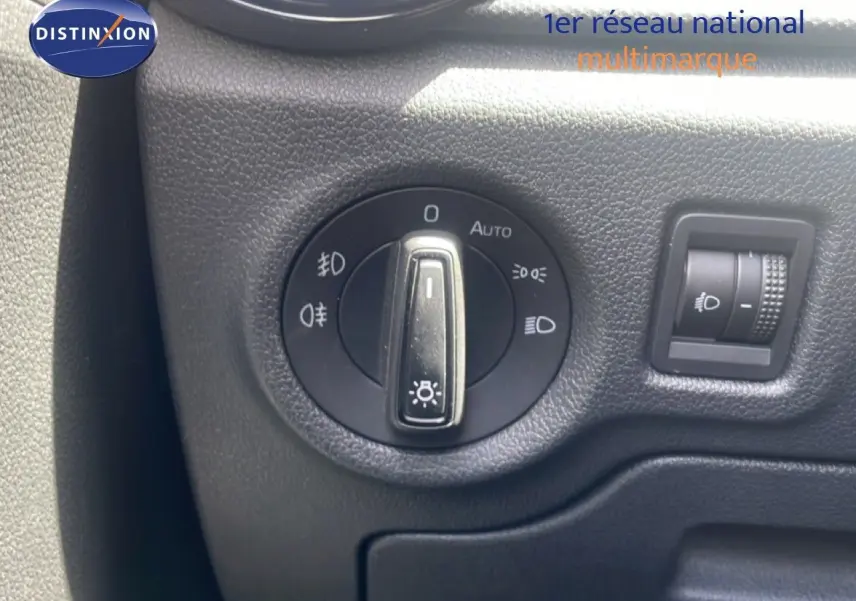 Gros plan sur le bouton de commande des phares d'une Skoda Fabia blanche, intérieur noir texturé visible.
