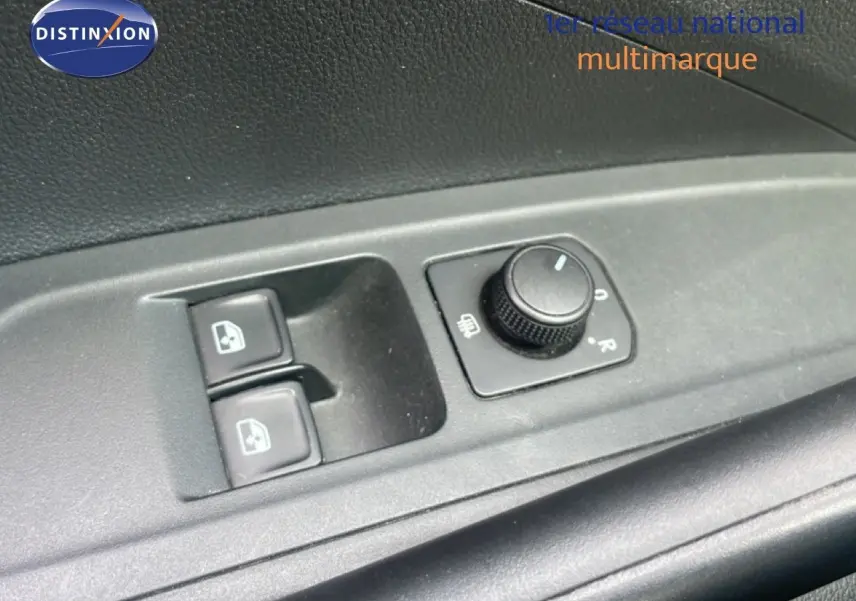 Gros plan sur les commandes de lève-vitres et réglage des rétroviseurs côté conducteur d'une Skoda Fabia blanche.