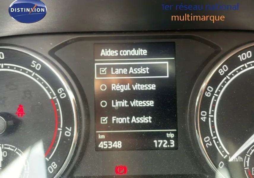 Tableau de bord de Skoda Fabia blanc Candy 2022 montrant l'écran des aides à la conduite et le compteur kilométrique.