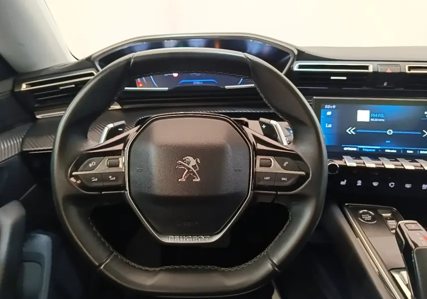 Vue rapprochée du volant cuir noir de la Peugeot 508 avec tableau de bord digital et écran tactile central.